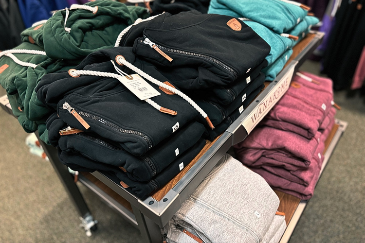 a table of folded wanakome womens hoodies in variety of colors.