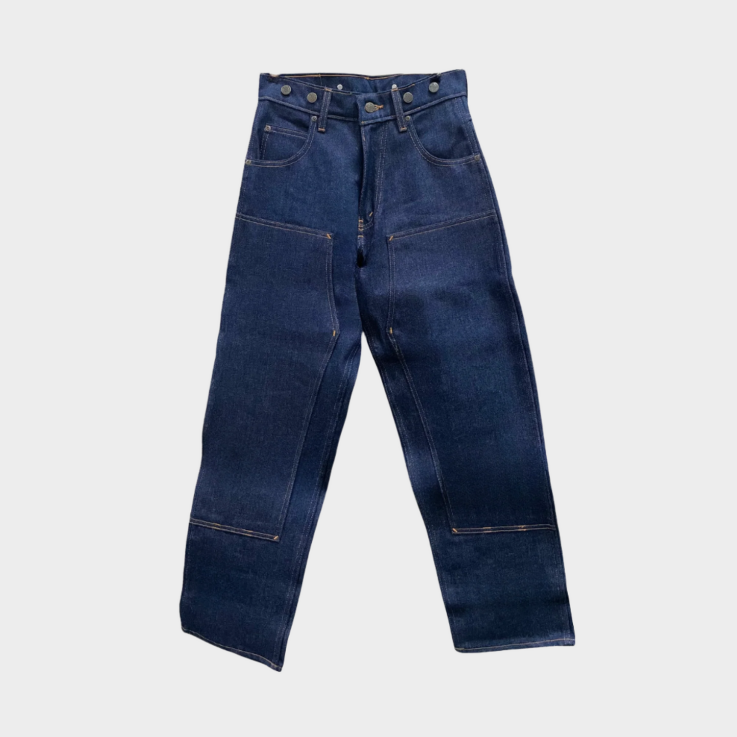 A pair of hanging blue work jeans with double panel front. Has suspenders buttons.