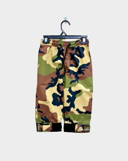 A pair of kids rain pants with an elastic waistband and drawstring. Ankles have a neoprene covered velcro adjustment. Shown in a classic camo pattern of green, brown, tan, and black