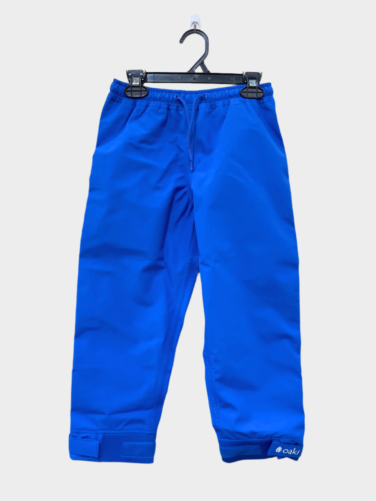 A pair of kids rain pants with an elastic waistband and drawstring. Ankles have a neoprene covered velcro adjustment. Shown in a bright mid blue