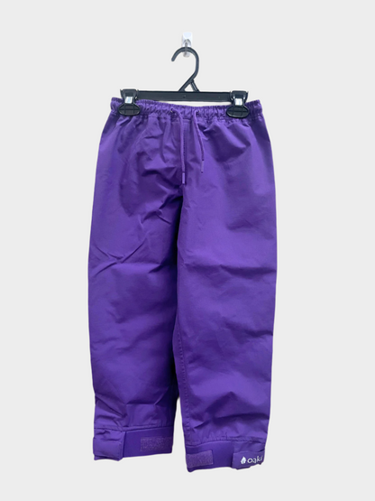 A pair of kids rain pants with an elastic waistband and drawstring. Ankles have a neoprene covered velcro adjustment. Shown in solid purple