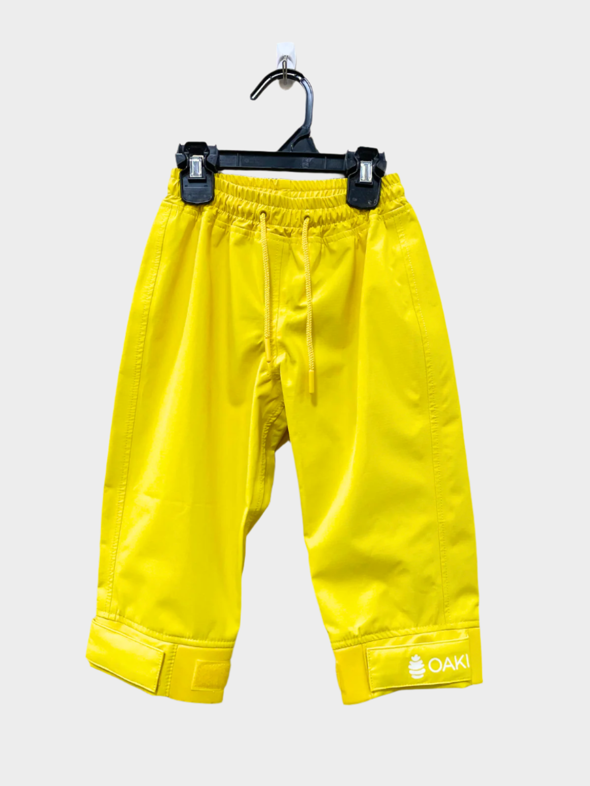 A pair of kids rain pants with an elastic waistband and drawstring. Ankles have a neoprene covered velcro adjustment. Shown in yellow