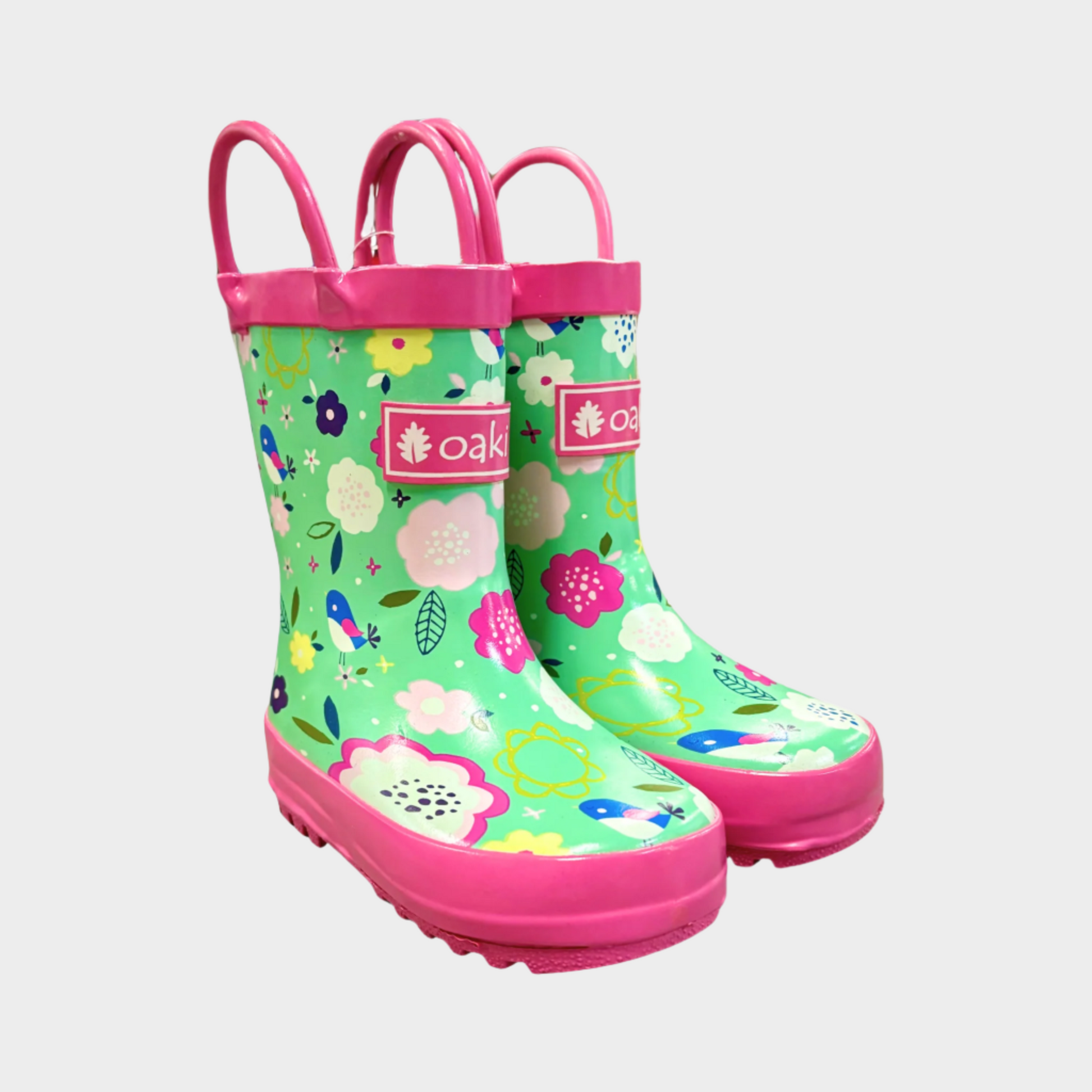 Kids rubber rain boots with pink and green floral pattern rubber and oaki logo. Black tread and loop handles.